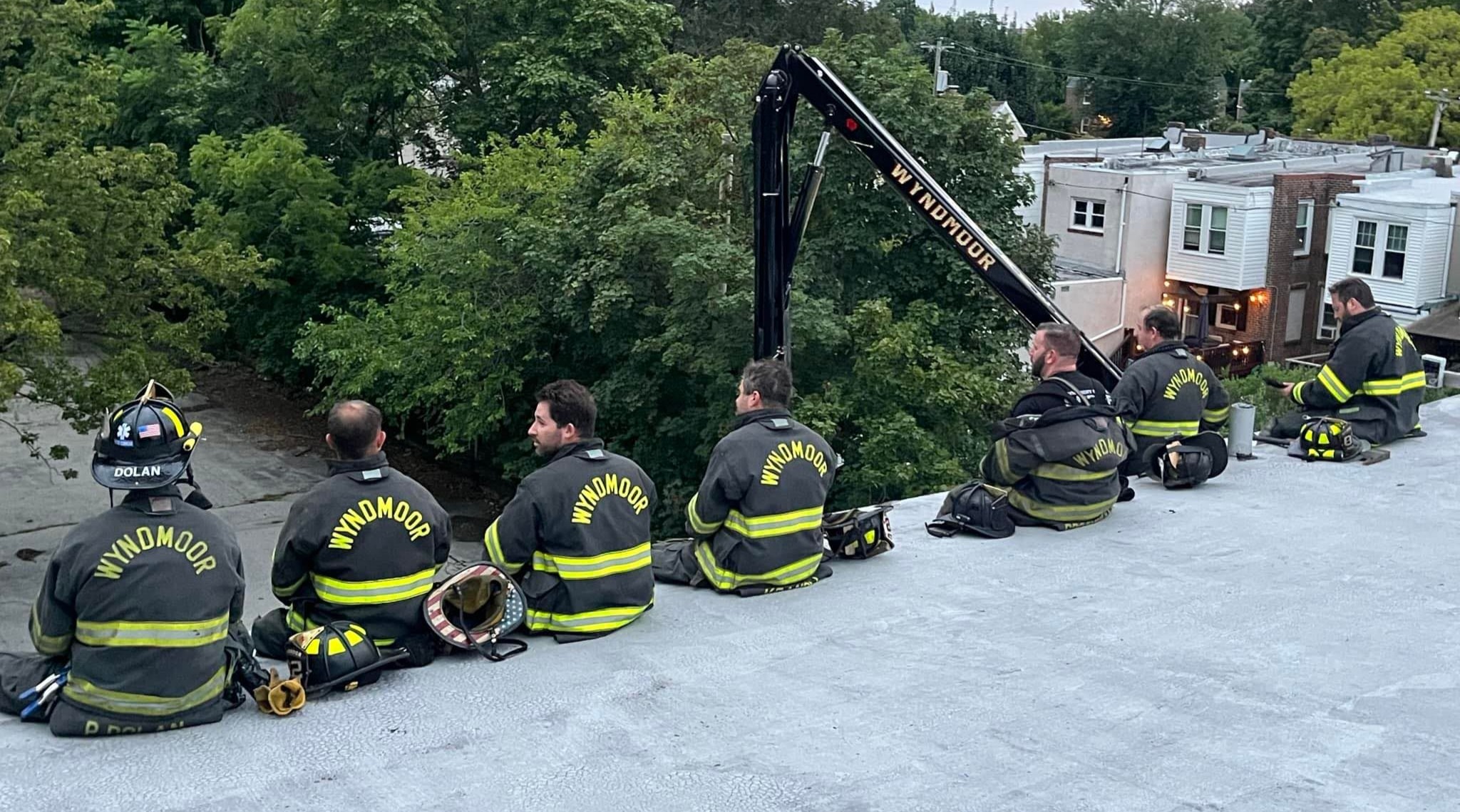 Wyndmoor firefighters resting on a rooftop at dusk after an incident